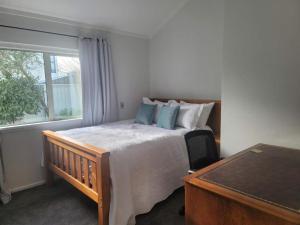 a bedroom with a bed and a desk and a window at The light Inn in Christchurch