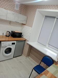 a kitchen with a washing machine and a blue chair at Астана in Ustʼ-Kamenogorsk