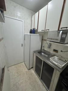 a small kitchen with a sink and a refrigerator at Quarto de Hóspedes a 3 min da praia in Rio de Janeiro