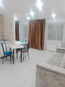 a living room with a table and chairs and a couch at Металлург in Ustʼ-Kamenogorsk