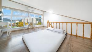 een witte slaapkamer met een bed en een groot raam bij Geoje Forest-Morning Spa Pension in Geoje 