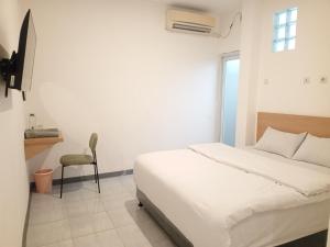 a white bedroom with a bed and a chair at JS Sentul City Syariah in Cibitung