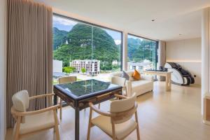 a living room with a table and chairs and a large window at Mountain Search Snow View Hotel (Yangshuo Water Ink Landscape Store) in Yangshuo