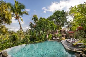 - une piscine au milieu d'un complexe avec des palmiers dans l'établissement Puri Gangga Resort Ubud, à Tegalalang
