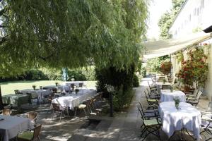 ein Restaurant mit Tischen und Stühlen unter einem Baum in der Unterkunft Hotel Landgut Burg GmbH in Weinstadt