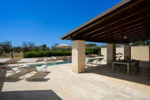 Un patio con mesa y sillas junto a una piscina. en Villa With Sauna And Gym In The Heart Of Puglia, en Oria