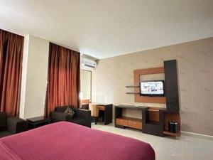 マナドにあるTravello Hotel Manadoのベッドとテレビがあるホテルの部屋