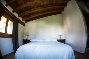 a bedroom with a white bed with a wooden ceiling at Hotel Mariñerune in Mungia