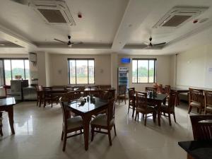 a dining room with tables and chairs and windows at Hotel Krishna Anandam in Vrindāvan