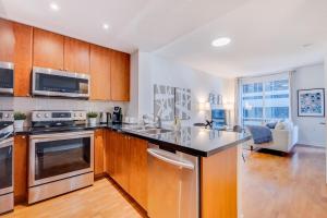 a kitchen with stainless steel appliances and wooden cabinets at 2BR Yorkville Condo - Self Check In & Free Parking in Toronto