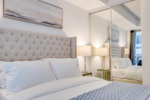 a bedroom with a white bed and a mirror at 2BR Yorkville Condo - Self Check In & Free Parking in Toronto
