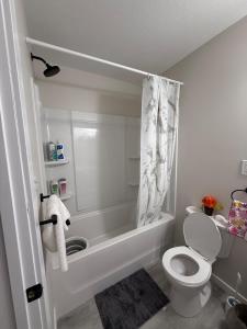 a bathroom with a toilet and a bath tub at Newly Built Cozy Cove Suite in Regina +26 photos
