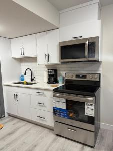 una cocina con estufa y microondas en Newly Built Cozy Cove Suite, en Regina
