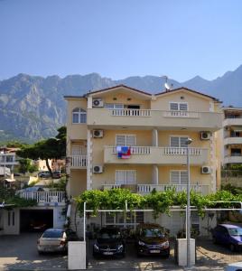 un gran edificio con coches estacionados en un estacionamiento en Apartments Ivica, en Makarska