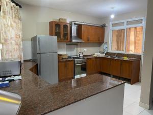 Una cocina con gabinetes de madera y un refrigerador de acero inoxidable. en Green top Cordier apartments, en Kampala