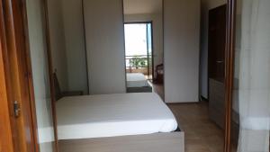 une chambre avec un lit blanc et un miroir dans l'établissement Appartamento Dellea, à Luino