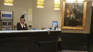 a woman talking on a cell phone at a cash register at Hotel Saint Cyr Etoile in Paris