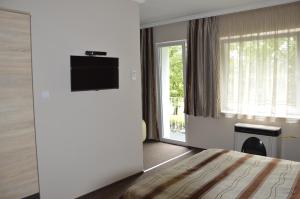 マコーにあるAdél Apartmanのベッドとテレビが備わるホテルルームです。