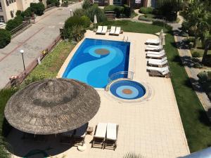 SoğucakにあるThe Pelican Penthouse at Kusadasi Golf Resortのパラソルと椅子付きのスイミングプールのオーバーヘッドビュー