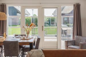 a dining room with a table and a glass door at Duinvilla Wetterwille in Makkum