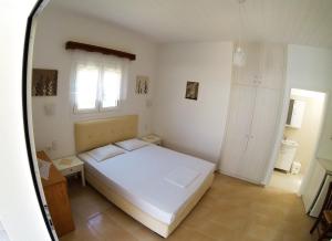 um quarto com uma cama branca e uma janela em Eleni Studios em Kefalos
