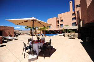 a table with aige umbrella and chairs and a table at Hotel Xaluca Dades in Boumalne