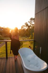 a woman standing on a porch with a bath tub at Architecturally designed cabin with outdoor bathtub and fireplace in Forcett
