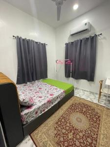 チャンルーンにあるVilla Cempaka Homestayの黒いカーテンとラグが敷かれた部屋のベッド