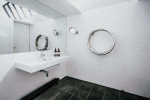 a white bathroom with a sink and mirrors at Alkina Lodge Yulu in Wattle Hill +33 photos
