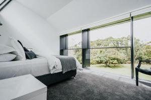 a bedroom with a bed and a large window at Alkina Lodge Yulu in Wattle Hill