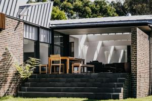 a patio with a table and chairs on a house at Alkina Lodge Yulu in Wattle Hill