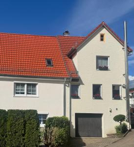 une grande maison blanche avec un toit rouge dans l'établissement Gästehaus mit 5 separaten Schlafzimmern für 9 Personen, 24 h check in direkte Nähe Landesgartenschau, à Aalen