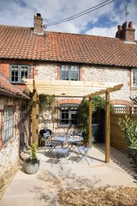 a wooden pergola in front of a house at No33 THORNHAM BOUTIQUE COTTAGES in Thornham