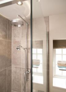 una doccia con porta in vetro in bagno di No33 THORNHAM BOUTIQUE COTTAGES a Thornham