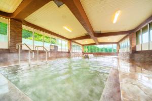 a large pool of water in a room with windows at Ooedo Onsen Monogatari Miyoshiya in Yumura