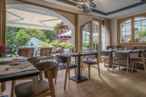 a restaurant with tables and chairs and windows at Hotel Eden Wellness in Zermatt