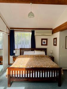 a bedroom with a bed and a large window at Cozy and quiet studio apartment with shared spa pool in Dunedin +3 photos