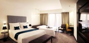 ポルトロスにあるHotel Slovenija - Terme & Wellness LifeClassのベッド2台と椅子があるホテルの部屋