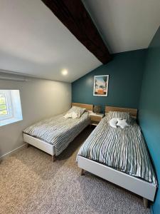 two beds in a bedroom with blue walls at Au pré des pierres in Sancé