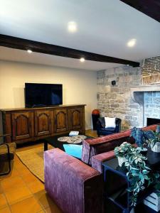 a living room with two couches and a flat screen tv at Au pré des pierres in Sancé