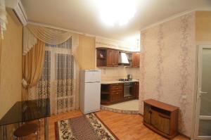 La cuisine est équipée d'un réfrigérateur blanc et de placards en bois. dans l'établissement VIP apartments on Admiralskaya, à Mykolaïv
