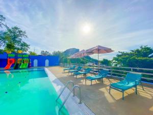 a pool with chairs and umbrellas next to a playground at Blue Wave Hotel Hua Hin in Hua Hin
