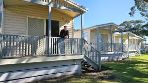 a man standing on the front porch of a house at Barrack Point Holidays in Barrack Point