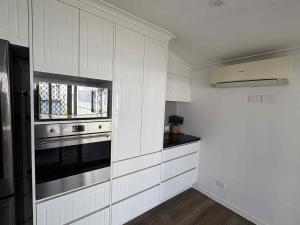 a kitchen with white cabinets and a stove top oven at Retreat on Murray - Pool, Playground, Huge Deck! in Rockhampton