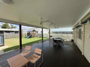 a screened porch with chairs and a table and a playground at Retreat on Murray - Pool, Playground, Huge Deck! in Rockhampton