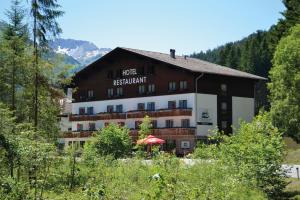 ein Hotel in den Bergen mit einem Sonnenschirm davor in der Unterkunft Hotel Styrolerhof in Steeg