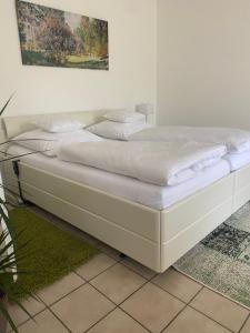 a white bed with white sheets and pillows on it at Gemütliche 2 Zimmer Ferienwohnung mit Terrasse Fernsehsessel Spülmaschine Grill Schaukel, fußläufig zu S-Bahn nach München und See, ideal zum Entspannen aber auch zum Arbeiten in Wörthsee +31 photos
