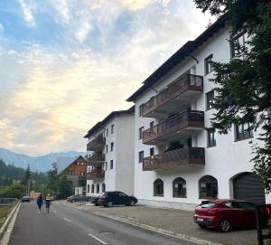 a white building with balconies on the side of a street at Panorama Pine Retreat - Spacious 2-Bedroom Flat in Predeal