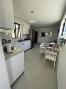 eine Küche mit weißen Schränken und einem Tisch und Stühlen in der Unterkunft Bright Coastal Penthouse with Huge Terrace Overlooking the Sea- Ghadira Mellieha in Is-Sellum