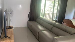 a leather couch in a living room with a window at Canal hut 2 - Chaloklum in Chaloklum